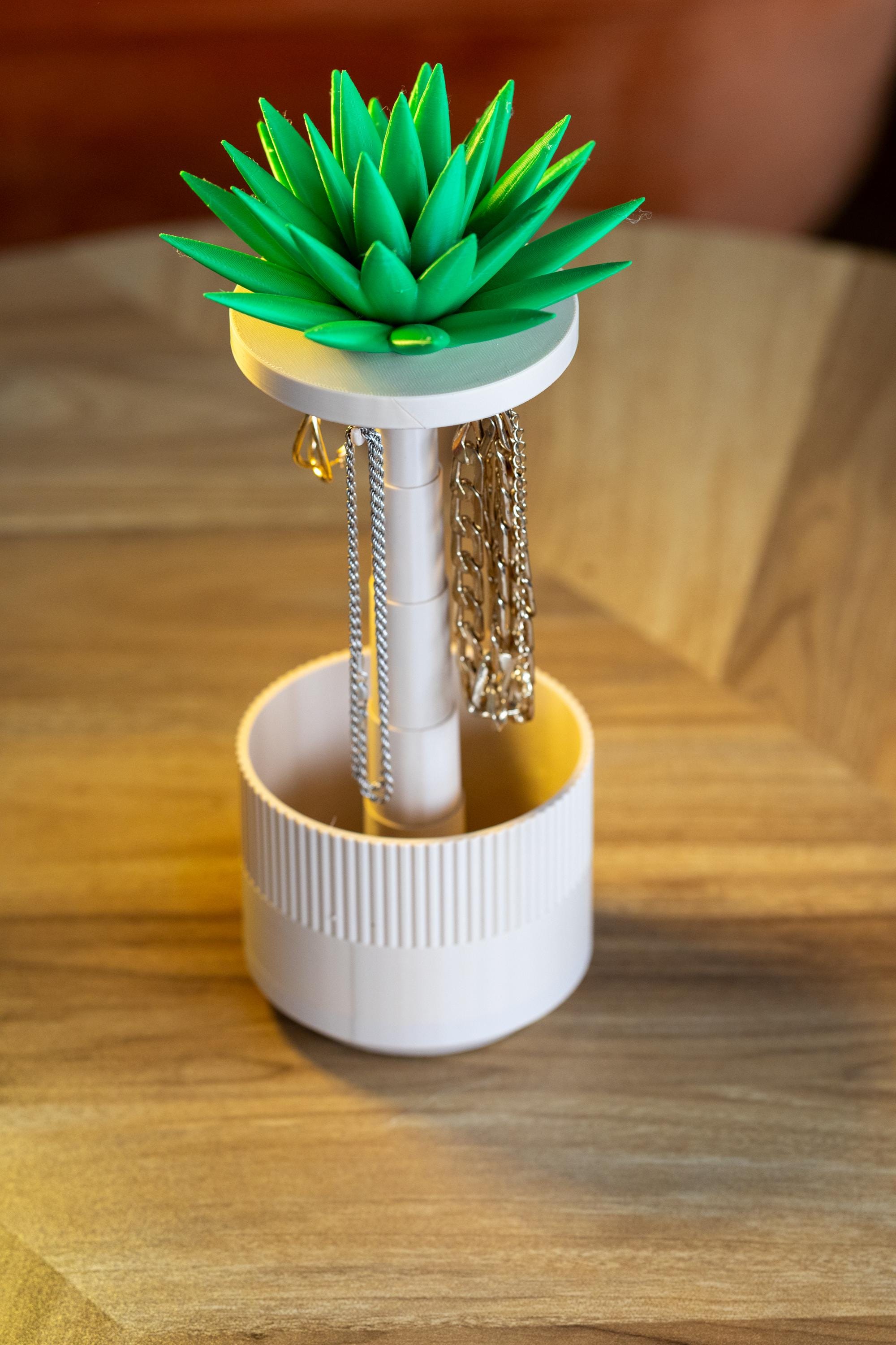 Necklace holder with green succulent design on a wooden surface